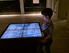 Ein kleiner Junge betrachtet Bildschirme im Rahmen einer Ausstellung