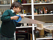 Junge sägt an einem Stück Holz
