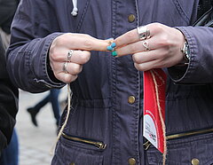 2 Hände von Frau mit blauen Fingernägeln machen Knoten in eine Schnur, die Bestandteil der Führung ist