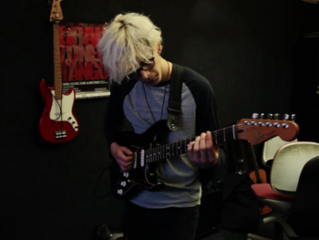 Ein junger Mann spielt Gitarre in einem Musikstudio. 
