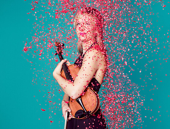 Foto einer Frau mit einer Geige in der Hand, Konfetti fällt von der Decke