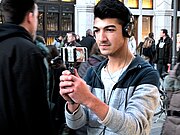 Ein Jugendlicher hat Kopfhörer auf und hält sein Handy mit einem Selfiestick und schießt Fotos