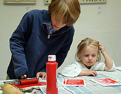 Ein Junge rollt Farbe über einen selbstgemachten Stempel
