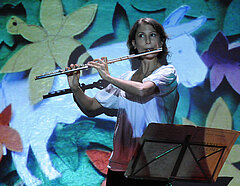 Eine Schaupielerin spielt Querflöte auf der Bühne