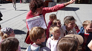 Eine Stadtführerin mit einer Gruppe von Kindern