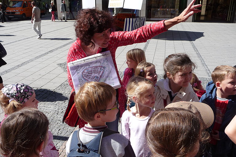 Eine Stadtführerin mit einer Gruppe von Kindern  