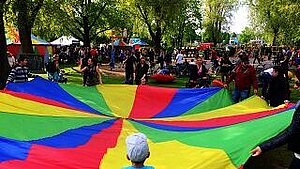 Kinder spielen mit einem großen Regenbogentuch.