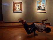 Ein Junge zeigt seine akrobatsichen Fähigkeiten vor ein paar Gemälden
