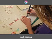 Ein Mädchen schneidet ein Stencil – eine Schablone – in Form einer „Peace-Zeichen-Hand“ aus, die später beim Sprühen eingesetzt werden soll.
