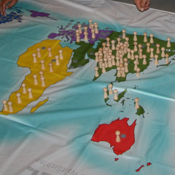 Kinder platzieren Spielfiguren auf der Weltkarte aus Stoff auf dem Boden