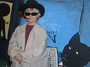 Ein Junge ist beim Kinder-Krimifest als Detektiv mit Sonnenbrille, langem Mantel und Pfeife verkleidet