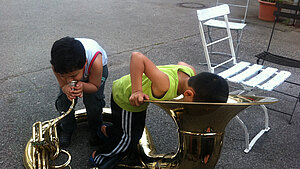Zwei Kinder spielen auf und mit einem Sousaphon (eine besondere Tuba).