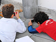Zwei Jungs liegen auf dem Boden und fotografieren Modelleisenbahn-Figuren
