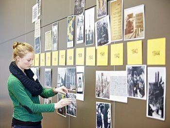 Ein Mädchen pinnt Zettel und Fotos an eine Wand