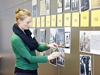 Ein Mädchen pinnt Zettel und Fotos an eine Wand