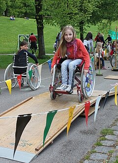 Ein Kind fährt mit einem Rollstuhl auf einem Parcours