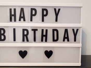 In einem beleuchteten Setzkasten ist mit Buchstaben gesetzt: "Happy Birthday".