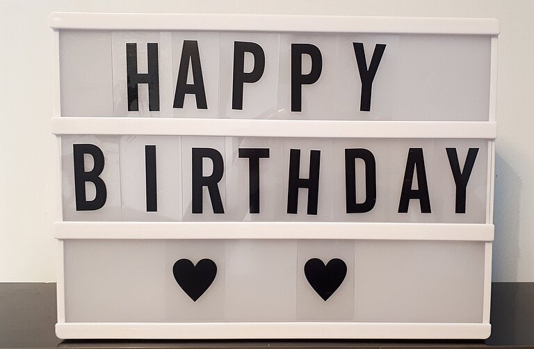 In einem beleuchteten Setzkasten ist mit Buchstaben gesetzt: "Happy Birthday".  