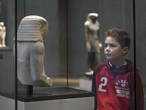 Ein Junge betrachtet eine ägyptische Figur