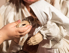 Kind hält die Hand einer Puppe