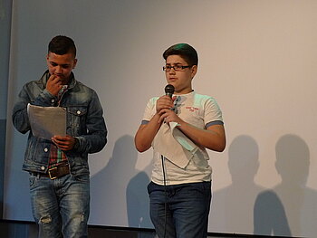 Zwei Jungen stehen bei einem Poetry Slam auf der Bühne