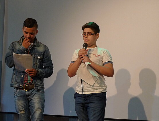 Zwei Jungen stehen bei einem Poetry Slam auf der Bühne