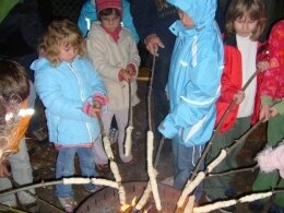 Kinder halten Stockbrot in ein Feuer