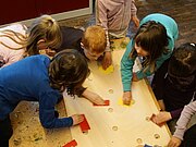 Mehrere Kinder spielen ein Brettspiel auf dem Boden