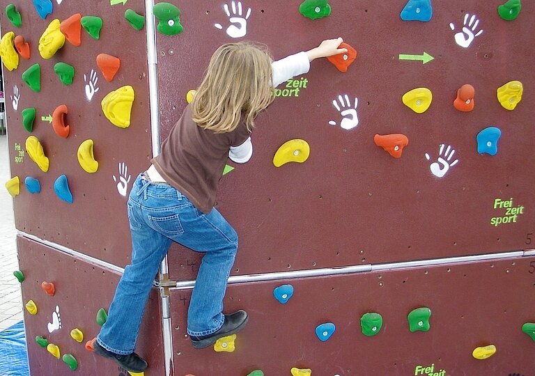 Ein Kind klettert an einer Boulderwand  