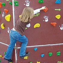 Ein Kind klettert an einer Boulderwand