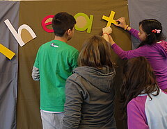 Kinder befestigen den Schriftzug "Theater" an einem Vorhang