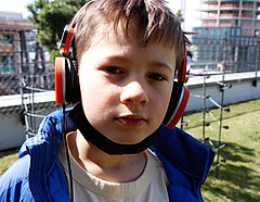 Ein Junge mit Kopfhörern auf den Ohren schaut einen an