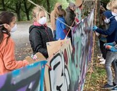 Kinder hängen Graffiti-Bilder an einer Wäscheleine auf
