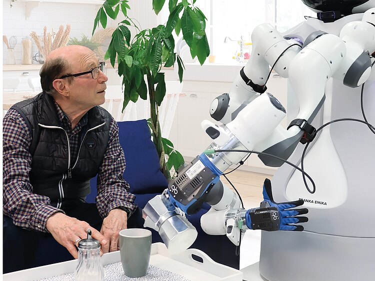 Ein älterer Mann bekommt Kaffee von einem Roboter eingeschenkt