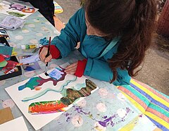 Ein Mädchen malt vertieft an einem farbigen Phantasiebild