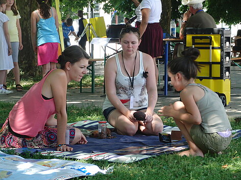Drei Frauen sitzen auf einer Decke auf einem Kulturfestival