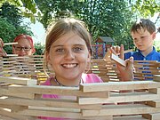 Kinder bauen einen Turm aus kleinen Holzplatten