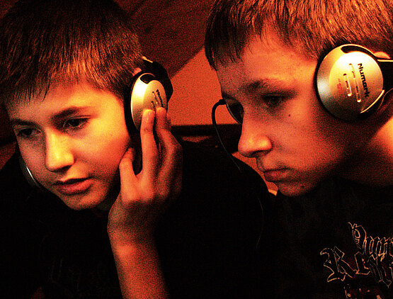 Kids nehmen Beats auf, hören konzentriert mit Kopfhörern ihre Musik ab