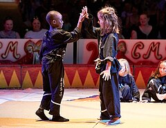 Ein Junge und ein Mädchen klatschen sich nach ihrem Auftritt in der Lilalu-Show ab (Workshop: Kampfkunst & Selbstbehauptung)