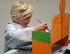 Ein Junge bemalt eine Holzfigur