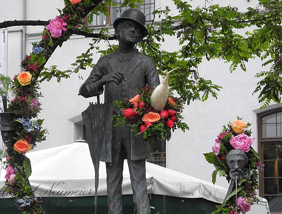 Bronzestatue des Valentin mit Blumenranken um sie herum