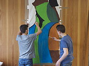 Zwei Jungen malen zusammen an einem Kunstwerk an der Wand