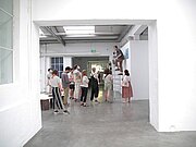 Der Künstler Samuel Fischer-Glaser zeigt einer Gruppe an Menschen von einer Leiter aus seine hebräische Buchsammlung.