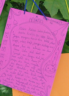Ein pinker Zettel mit einem Gedicht einer Teilnehmerin hängt an einer Pflanze