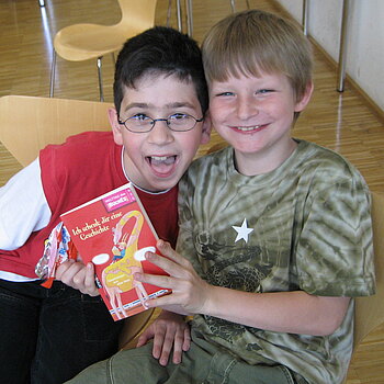 Zwei junge Leser mit Freude in der Bibliothek der Stiftung Pfennigparade