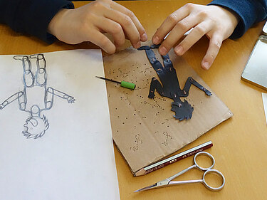 Junge bastelt eine bewegliche Figur aus Papier für einen Filmworkshop