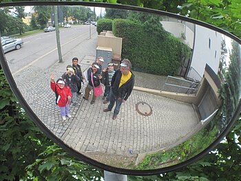 In dem Spiegel einer Einfahrt ist eine Gruppe an Kindern zu sehen