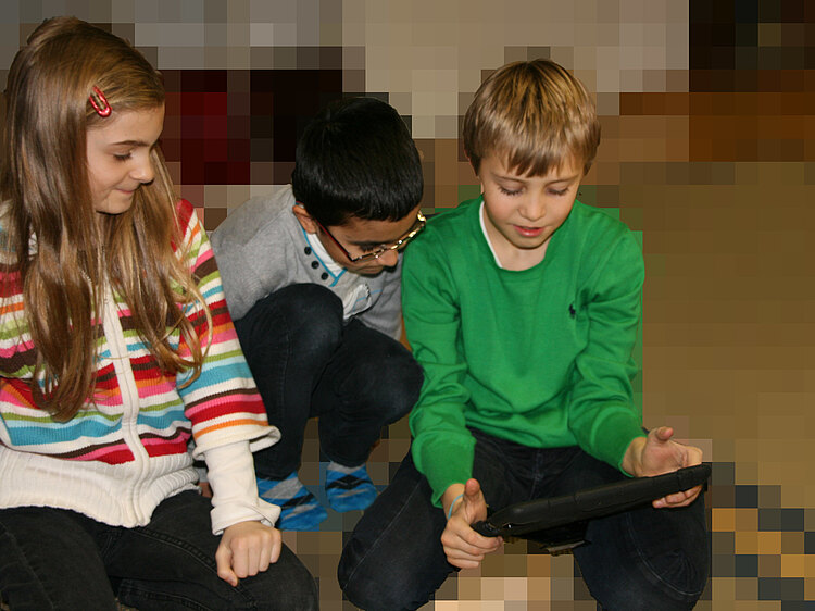 Drei Kinder spielen an einem iPad