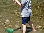 Ein Junge steht im Wasser und sammelt Wasserproben