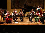 Ein Orchester spielt in traditioneller Kleidung ein Stück auf der Bühne